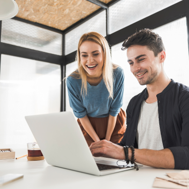Junge Mann und junge Frau, die zusammen auf einen Laptop schauen